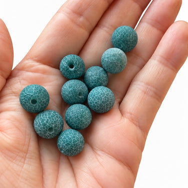 Matte agatperler i dæmpet petrol vist i hånden, 11–12 mm